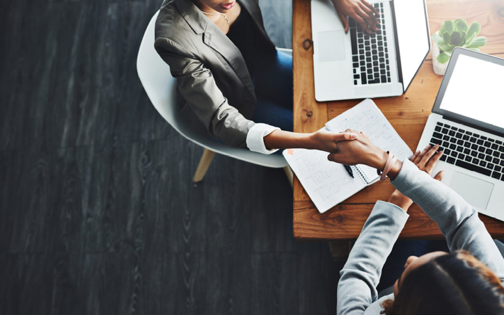 High angle shot of two businesswomen shaking hands in an office.