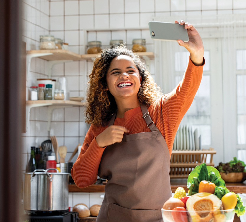 woman taking selfie with smartphone while cooking in kitchen