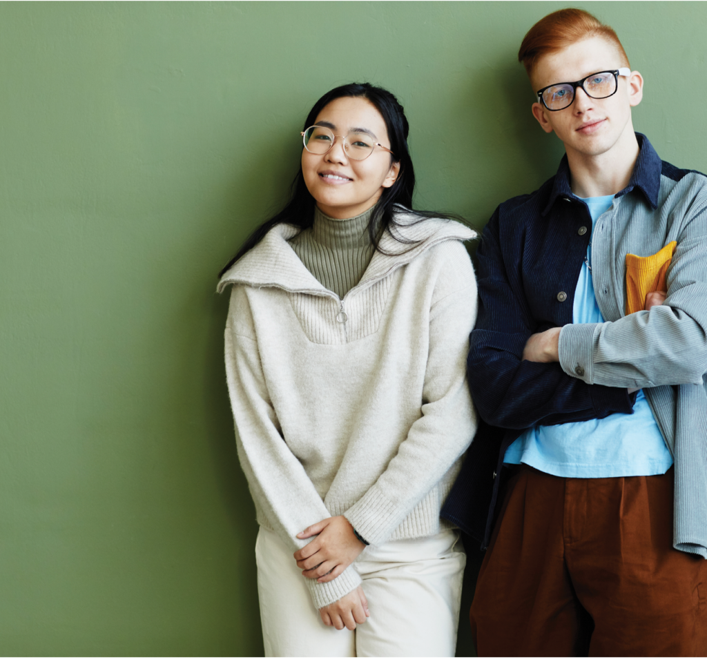 Candid waist up portrait of creative couple looking at camera while standing against green wall