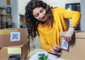 Woman affixing QR codes onto storage boxes.