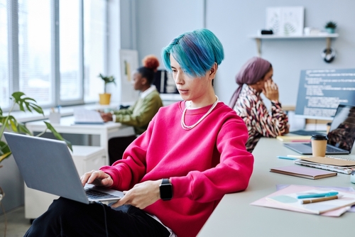 Portrait of Asian young man with colored hair using laptop